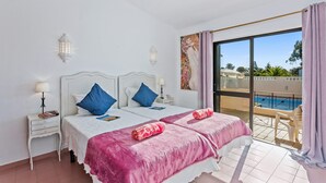 Ein Hotelzimmer mit zwei Betten, einem Balkon mit Blick auf den Pool und einem Bild an der Wand.