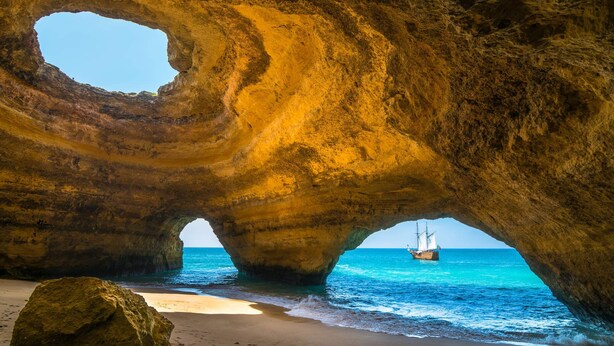Une formation rocheuse naturelle offrant une vue dégagée sur la mer et permettant d’apercevoir un bateau.