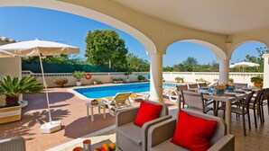 Un espace extérieur abrité comprenant une piscine, des chaises longues et des tables à manger.