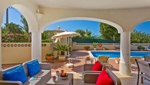 Une terrasse extérieure aménagée avec des meubles en osier, une piscine et des plantes en pot.