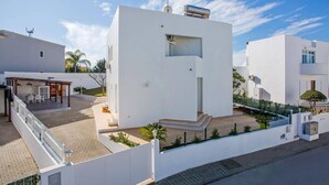 Un edificio moderno de color blanco con techo plano, una ventana pequeña y un tanque de agua en el techo.