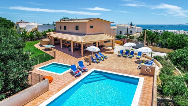A pool area with two pools, lounge chairs, and a covered seating area. - Villa Miranda by Villa Plus (Albufeira)