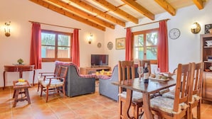 A cozy room with a wooden ceiling, a television, a dining table with chairs, and a sofa. - Villa Joan Toni by Villa Plus (Pollença)