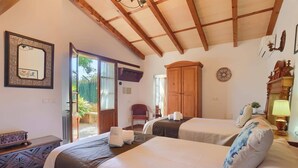 A bedroom with two beds, a wooden ceiling, a mirror, and a door leading to a balcony. - Villa Joan Toni by Villa Plus (Pollença)