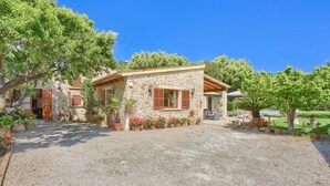 A stone house with a gravel driveway, wooden shutters, and potted plants. - Villa Joan Toni by Villa Plus (Pollença)