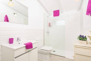 Ein modernes Badezimmer mit Duschkabine aus Glas, weißen Fliesen und einem weißen Waschbecken mit Spiegel darüber.