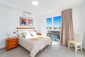 Quarto com cama, mesas de cabeceira, uma cadeira, janela com vista e obras de arte na parede.