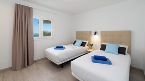 A hotel room with two beds, a window with a view, and a curtain. - Villa La Nueva by Villa Plus (Playa Blanca)