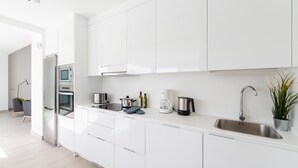 A modern kitchen with white cabinets, a stainless steel sink, and a coffee maker. - Villa La Nueva by Villa Plus (Playa Blanca)