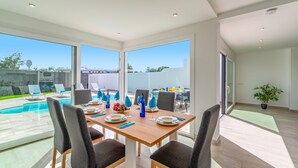 A dining area with a view of a swimming pool and outdoor seating. - Villa La Nueva by Villa Plus (Playa Blanca)