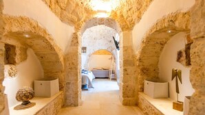 A narrow stone corridor with an arched ceiling leading to a bedroom.