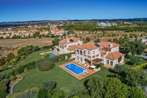 A large, multi-story house with a swimming pool and a well-maintained garden.