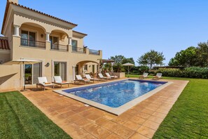A two-story house with a swimming pool, outdoor seating, and a well-maintained garden.