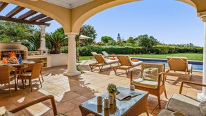 Eine Terrasse im Freien mit Pool, Liegestühlen und Grillplatz.