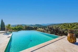 Une piscine rectangulaire à l’eau d’un bleu cristallin, entourée d’une terrasse carrelée.