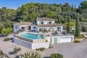 Une maison à deux étages avec une piscine, un espace salon extérieur et un garage.