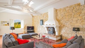 A modern living room with a stone wall, a fireplace, and a large window. - Villa Les Etoiles by Villa Plus (Lorgues)