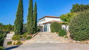 A villa with a stone pathway leading to a white building with green shutters, surrounded by cypress trees and a well-maintained garden. - Villa Les Etoiles by Villa Plus (Lorgues)