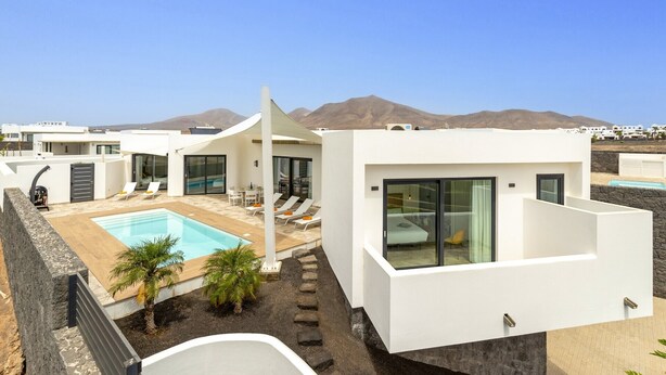 Een modern resort met een zwembad, terras en uitzicht op de bergen.