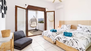 Ein Schlafzimmer mit Bett, Stuhl, Hängesessel und Blick ins Freie.