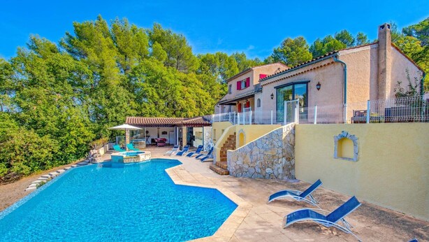 Una piscina con sillas de descanso, una escalera de piedra y un edificio con techo de tejas.
