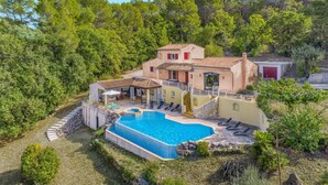 Una villa de estilo mediterráneo con piscina, mobiliario de exterior y un exuberante jardín.