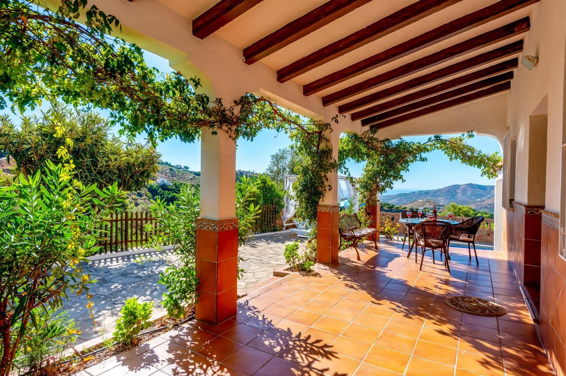 Un porche cubierto con vistas al campo, que incluye una mesa y sillas.