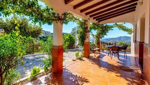 Une terrasse couverte avec vue sur la campagne, comprenant une table et des chaises.