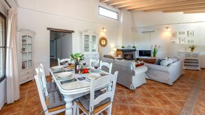 Un vaste espace de vie comprenant une table à manger dressée pour le repas, une cheminée et un coin salon confortable.