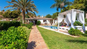 Une villa dotée d’une piscine, d’un espace salon extérieur abrité et d’une végétation luxuriante.