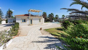 A two-story house with a tiled roof, a covered patio, and a paved driveway leading to a swimming pool. - Villa Clara Ispica by Villa Plus (Santa Maria del Focallo)