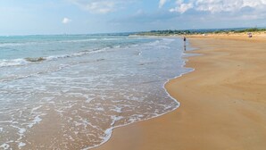 A wide sandy beach with gentle waves, a clear sky, and a distant city skyline. - Villa Clara Ispica by Villa Plus (Santa Maria del Focallo)
