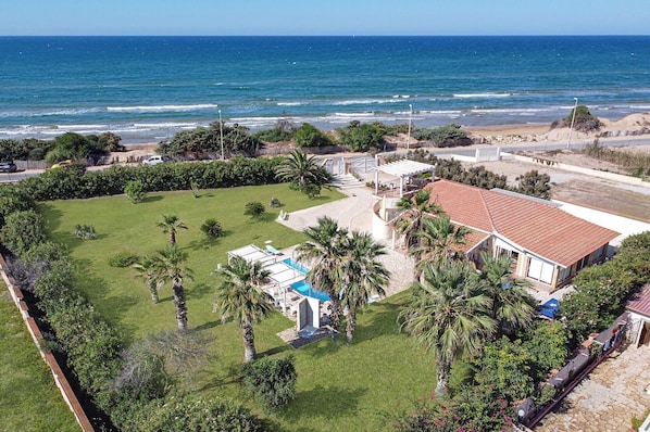 Enjoy breathtaking ocean views from this property's spacious lawn, featuring a pool and palm trees.