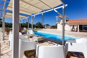 Relax by the serene pool surrounded by lounge chairs and a shaded pergola.