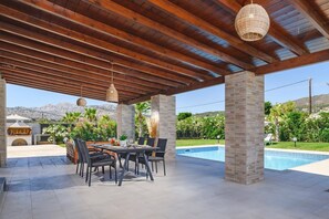 An outdoor patio with a pool, wooden ceiling, and stone pillars. - Villa Kalathos by Villa Plus (Kalathos)