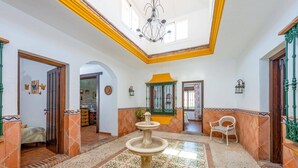 A spacious hallway with a fountain, tiled flooring, and a high ceiling with a skylight. - Villa Maravillas by Villa Plus (Frigiliana)