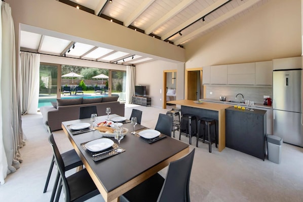 A modern kitchen with a dining area, a pool, and a TV.