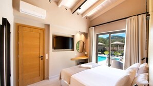 A bedroom with a large bed, a TV mounted on the wall, a wooden door, and a view of a swimming pool and outdoor area. - Villa Masticha Sweet by Villa Plus (Kariotes)