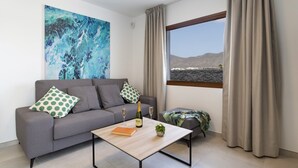 A modern living room with a grey sofa, a wooden coffee table, and a large abstract painting. - Villa Femes by Villa Plus (Playa Blanca)