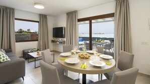 A modern living room with a dining area, large windows, a flat-screen TV, and a view of the sea. - Villa Femes by Villa Plus (Playa Blanca)