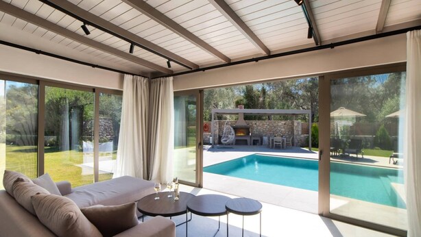A modern interior with a pool, outdoor seating, and a stone fireplace. - Villa Pasteli Sweet by Villa Plus (Kariotes)