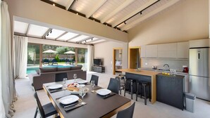 A modern kitchen with a dining area, a pool, and a TV. - Villa Pasteli Sweet by Villa Plus (Kariotes)