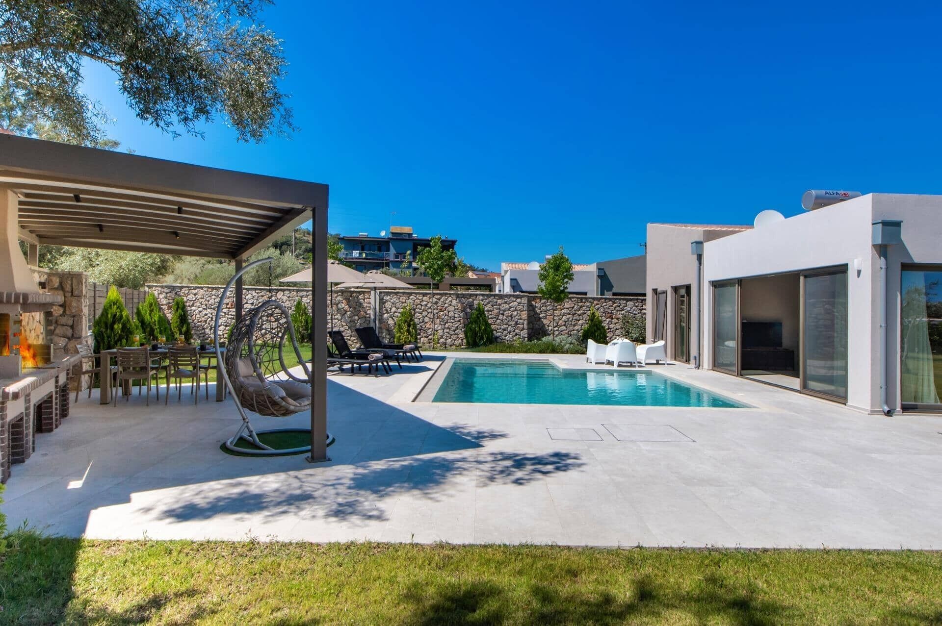 Un espace piscine extérieur moderne, agrémenté d’un mur en pierre, d’un fauteuil suspendu et d’un coin salon abrité.