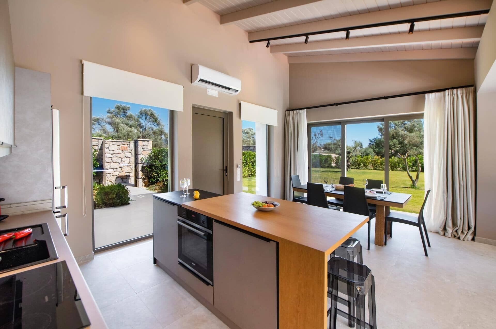 A modern kitchen with an island, a dining area with a table and chairs, and a view of a garden.
