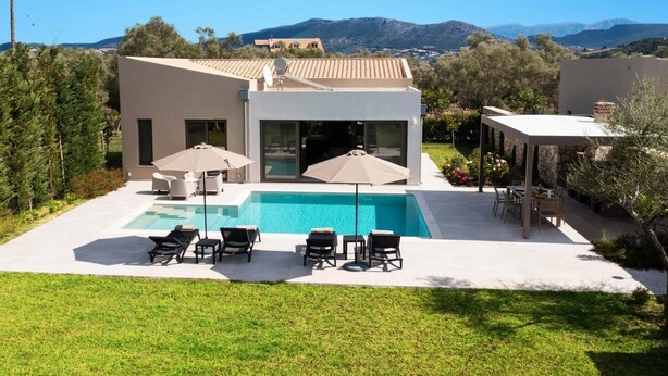 A modern house with a swimming pool, outdoor seating, and a view of mountains. - Villa Mandola Sweet by Villa Plus (Kariotes)
