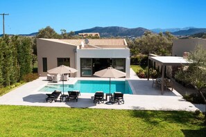 A modern house with a swimming pool, outdoor seating, and a view of mountains. - Villa Mandola Sweet by Villa Plus (Kariotes)