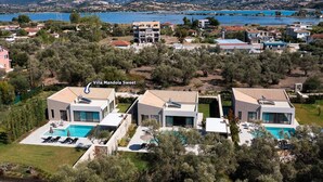 A modern villa with a swimming pool, surrounded by olive trees and a view of a lake and mountains. - Villa Mandola Sweet by Villa Plus (Kariotes)