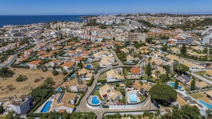An aerial view of a coastal residential area with numerous houses, some with swimming pools, and a clear view of the sea. - Villa Damasco by Villa Plus (Albufeira)