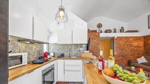 A modern kitchen with white cabinets, a microwave, and a wooden countertop. - Villa Damasco by Villa Plus (Albufeira)