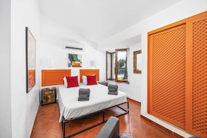 Ein Schlafzimmer mit einem Bett, zwei Kissen, einem Nachttisch, einem Fenster und einer Schiebetür.